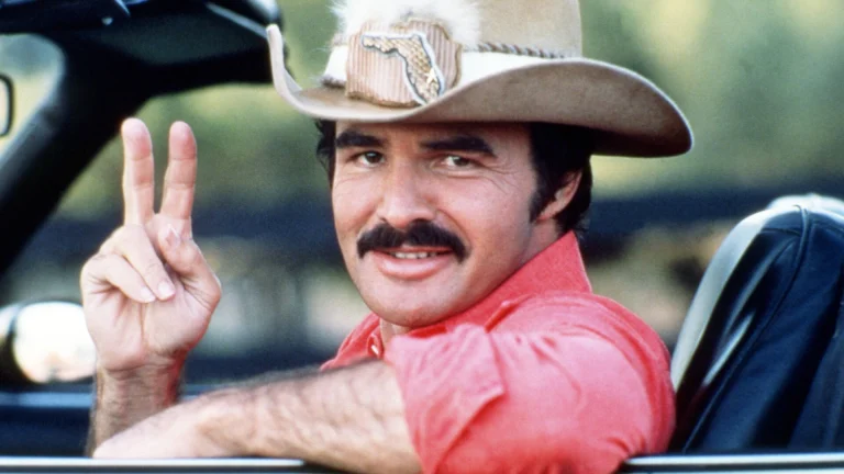 Burt Reynolds leaning out of a car window, smiling