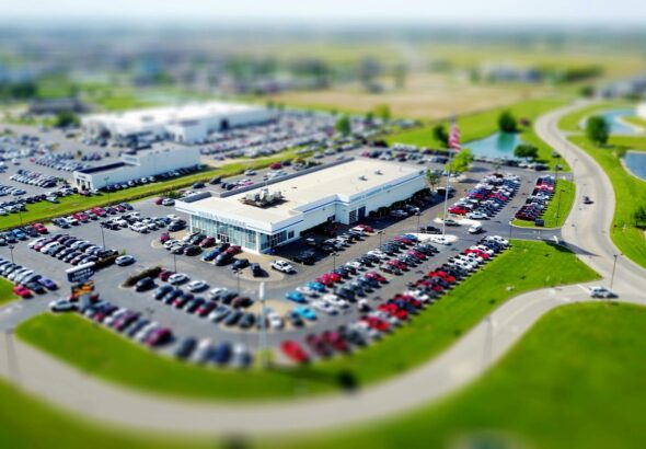 Aerial view of a car dealership lot with rows of new vehicles