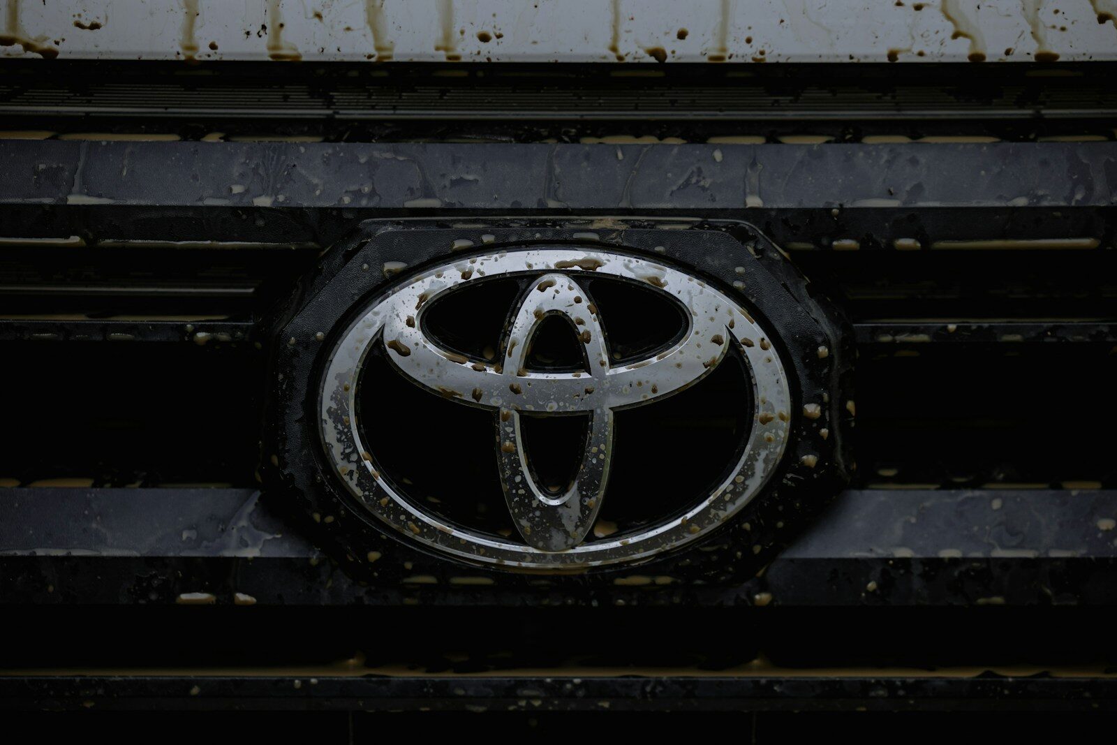 Close up of a dirty toyota car emblem on grille.