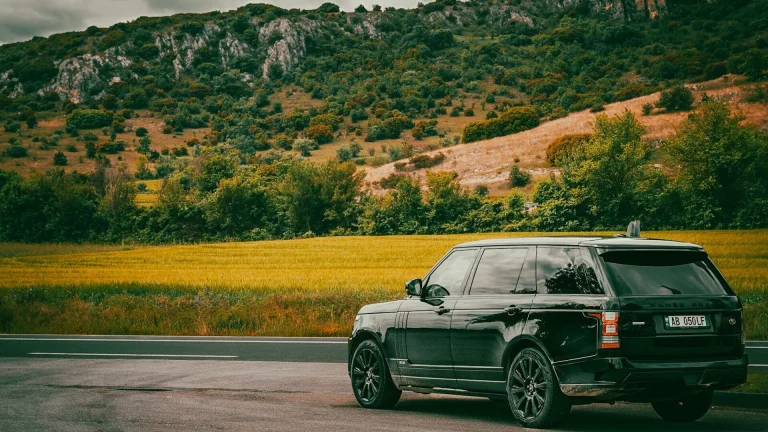 Black suv parked near scenic mountains and fields.
