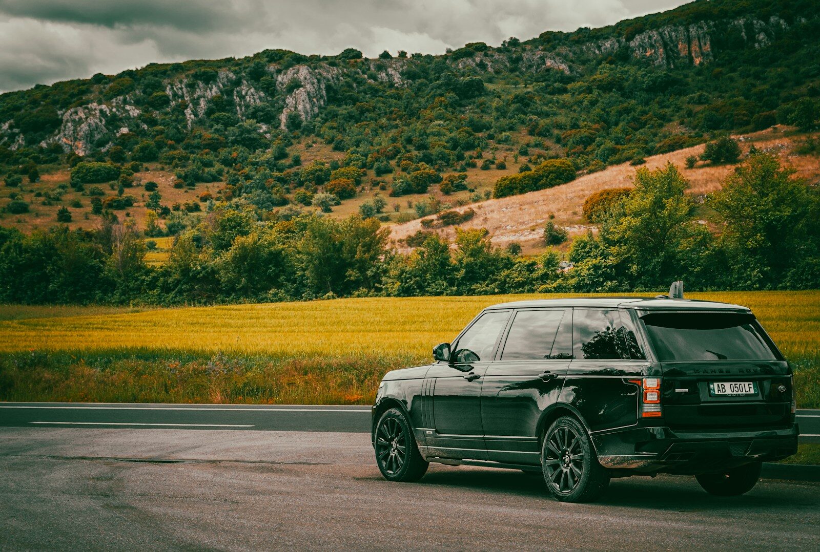 Black suv parked near scenic mountains and fields.