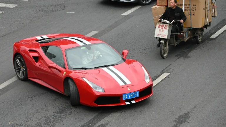 Red ferrari driving on a street with other vehicles.
