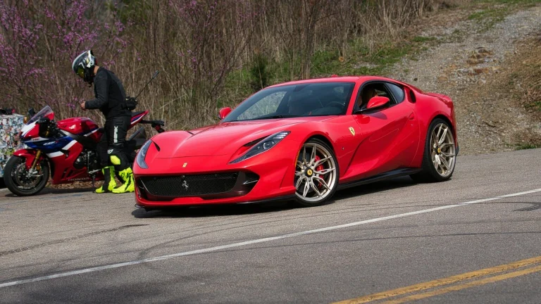 Red sports car parked next to a motorcycle