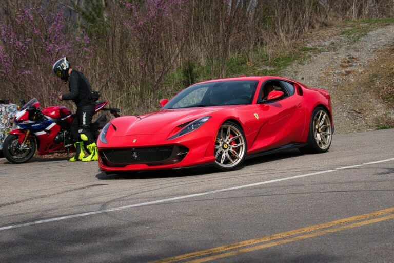 Red sports car parked next to a motorcycle