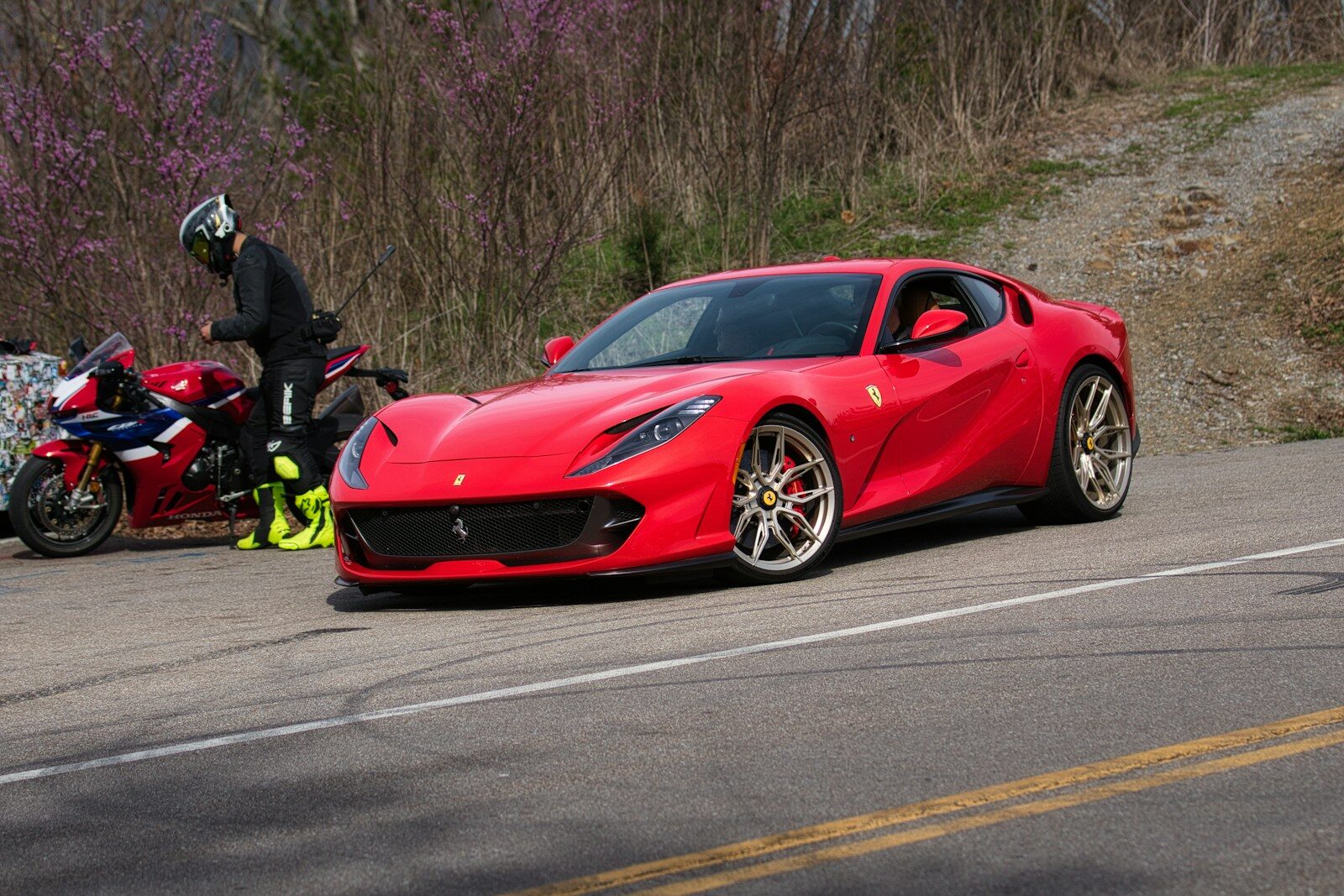 Red sports car parked next to a motorcycle
