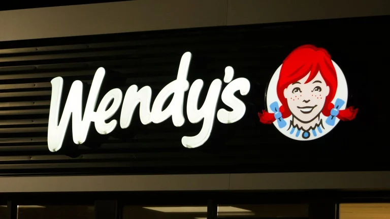 A wendy's sign is lit up at night