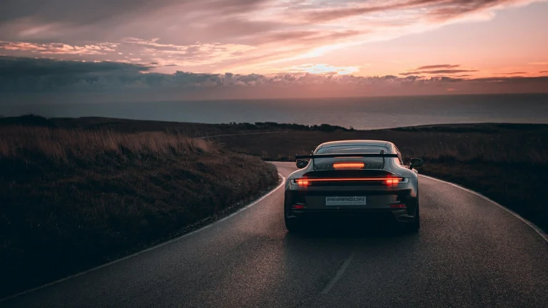 A car driving down a road with a sunset in the background