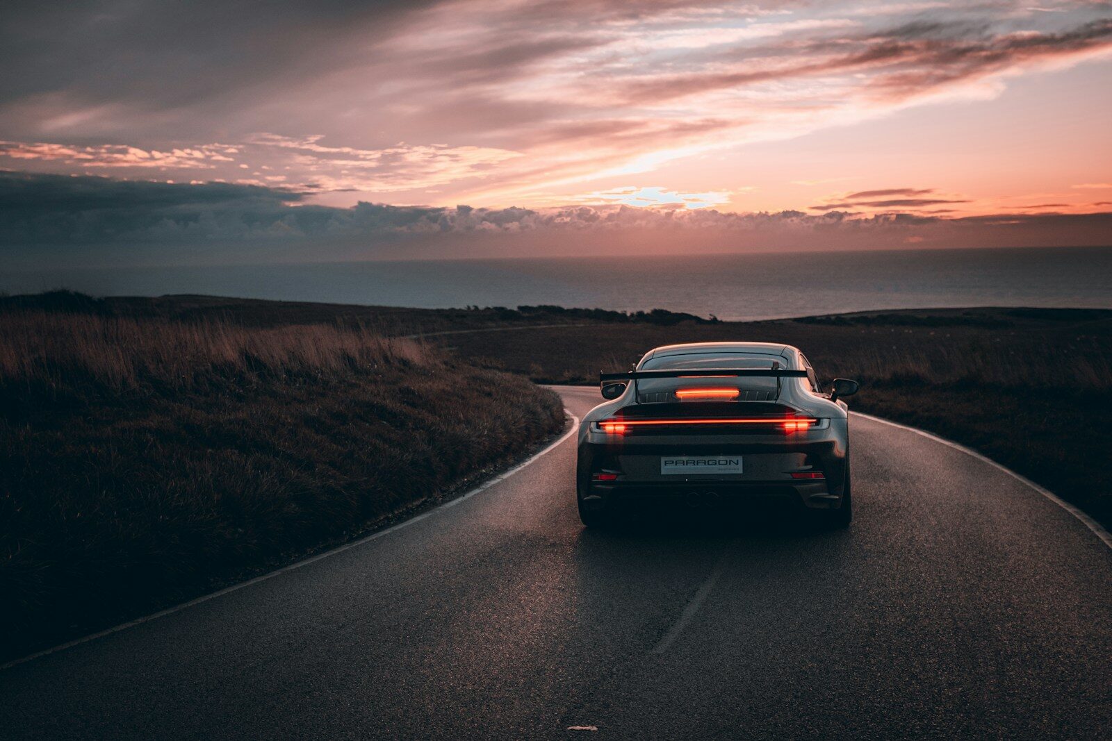 A car driving down a road with a sunset in the background