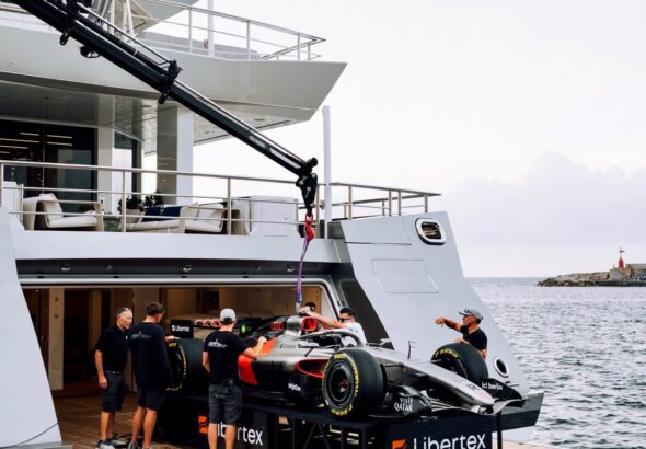 Formula 1 car being loaded onto a luxury superyacht in Monaco harbor during Grand Prix week