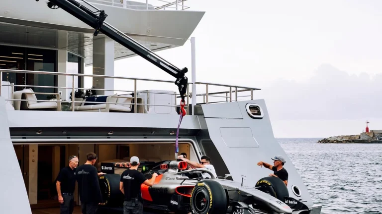 Formula 1 car being loaded onto a luxury superyacht in Monaco harbor during Grand Prix week