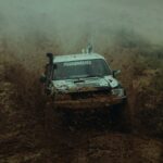 a white truck driving through a muddy field