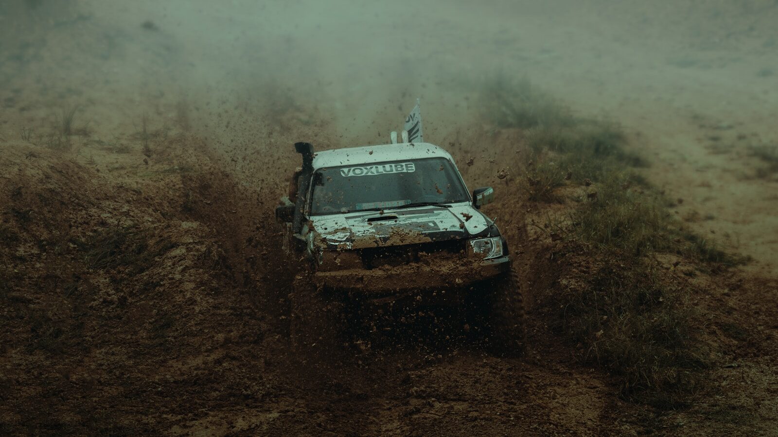 a white truck driving through a muddy field