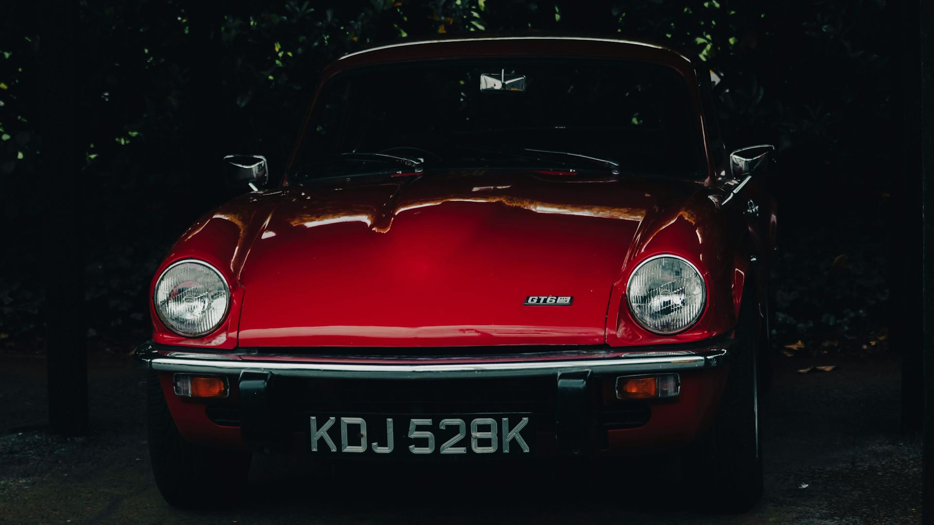 Red Aston Martin GT6 classic British sports car parked outdoors