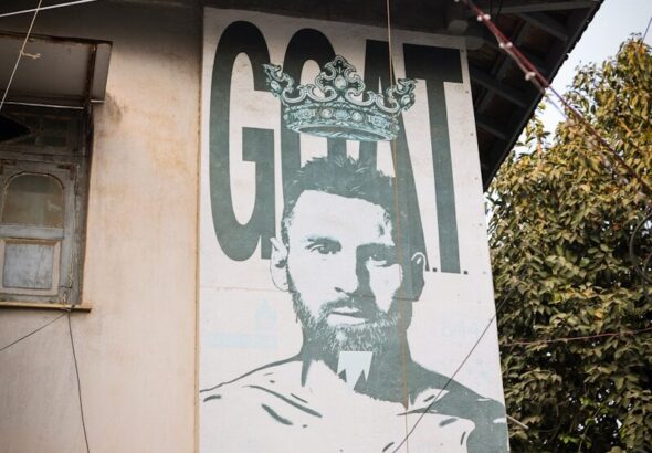 Mural of a soccer player with the word goat.