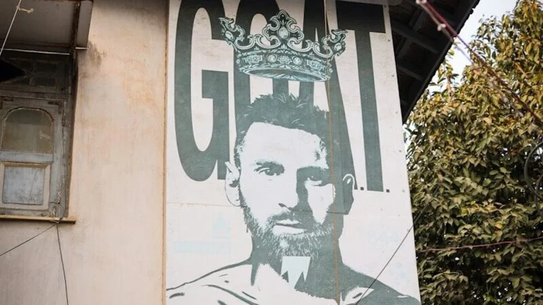 Mural of a soccer player with the word goat.