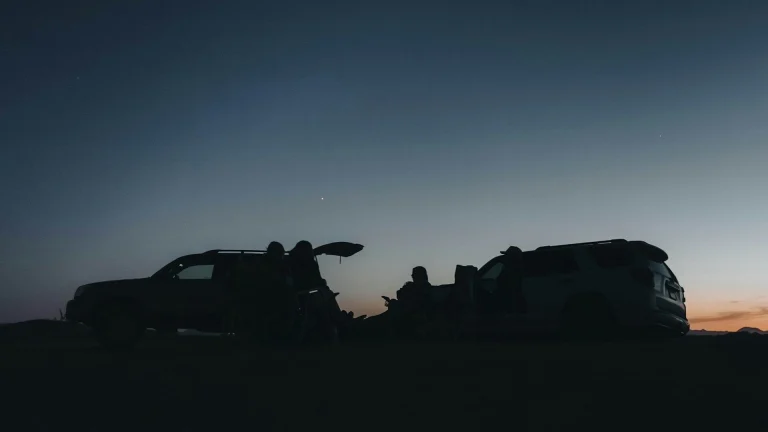 People sit around cars during dusk.