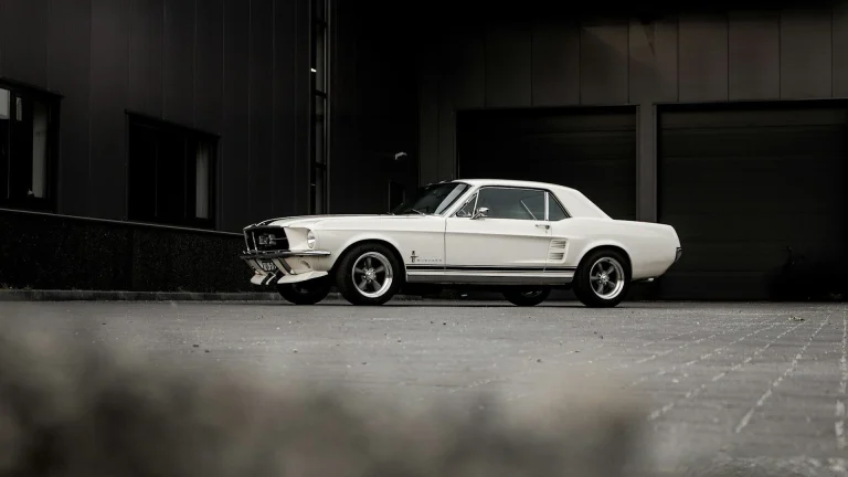 white sedan parked beside brown wall
