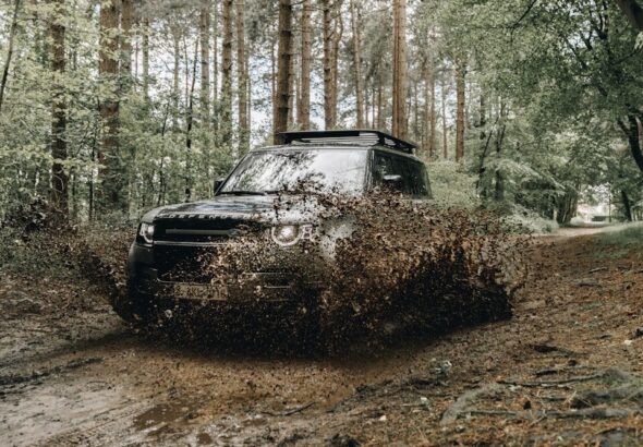 black car on dirt road in between trees during daytime