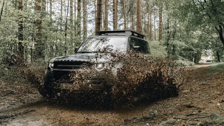 black car on dirt road in between trees during daytime