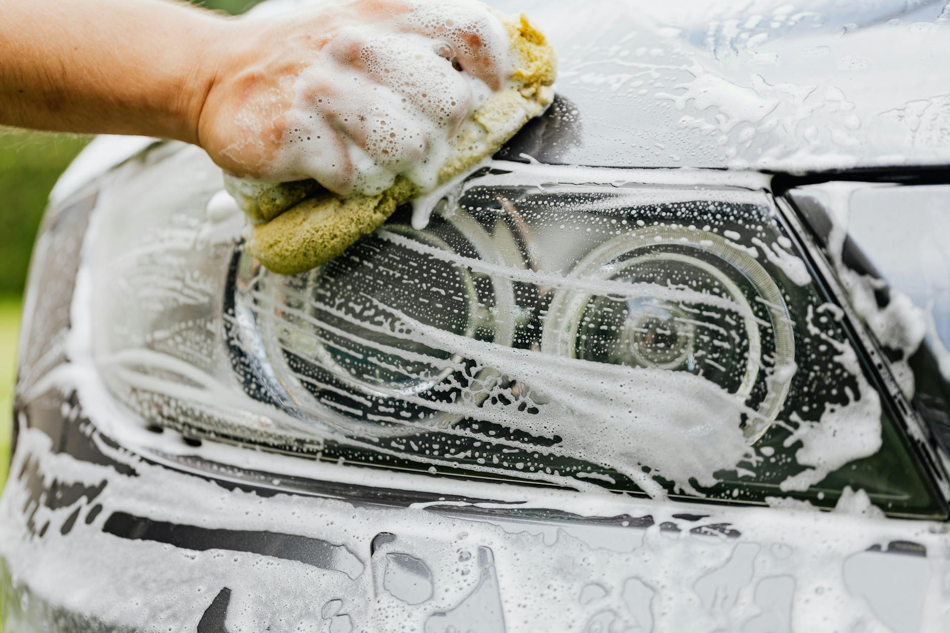 a person washing a the headlight of a car