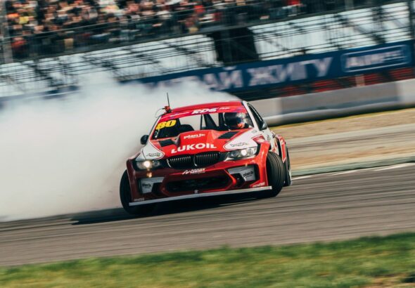 a red car driving down a race track with a lot of smoke coming out of