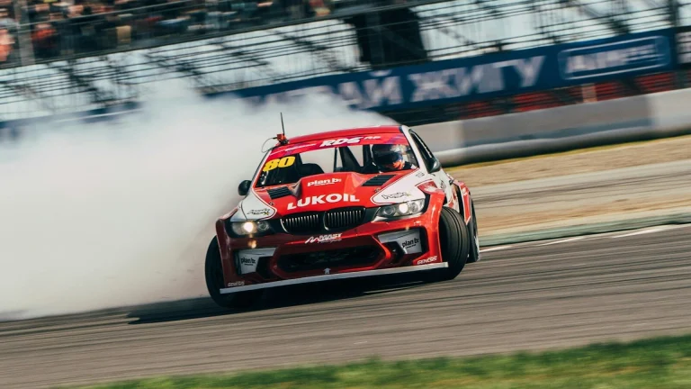a red car driving down a race track with a lot of smoke coming out of