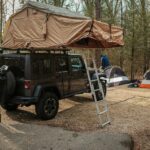 a van with a tent and a ladder in front of it