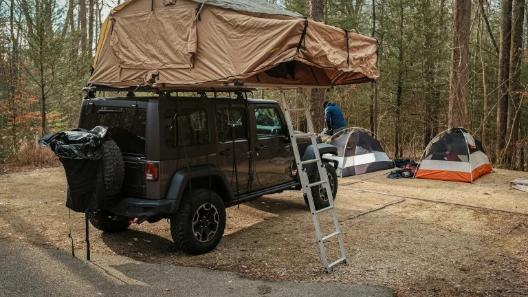 a van with a tent and a ladder in front of it