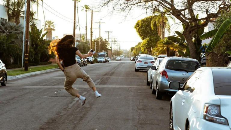 woman in black long sleeve shirt and white pants walking on street during daytime