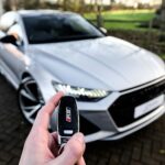 a person holding a car key in front of a silver car