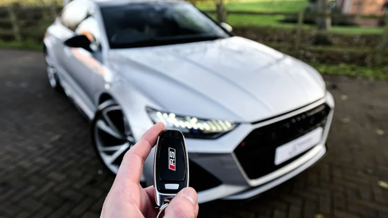 a person holding a car key in front of a silver car