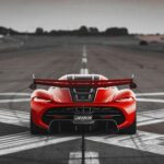 a red sports car driving down a runway