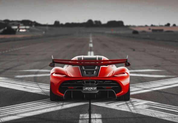a red sports car driving down a runway