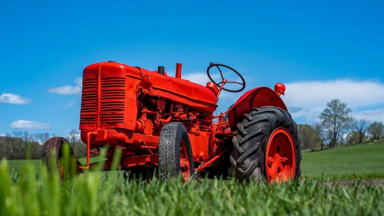 a red tractor is parked in the grass