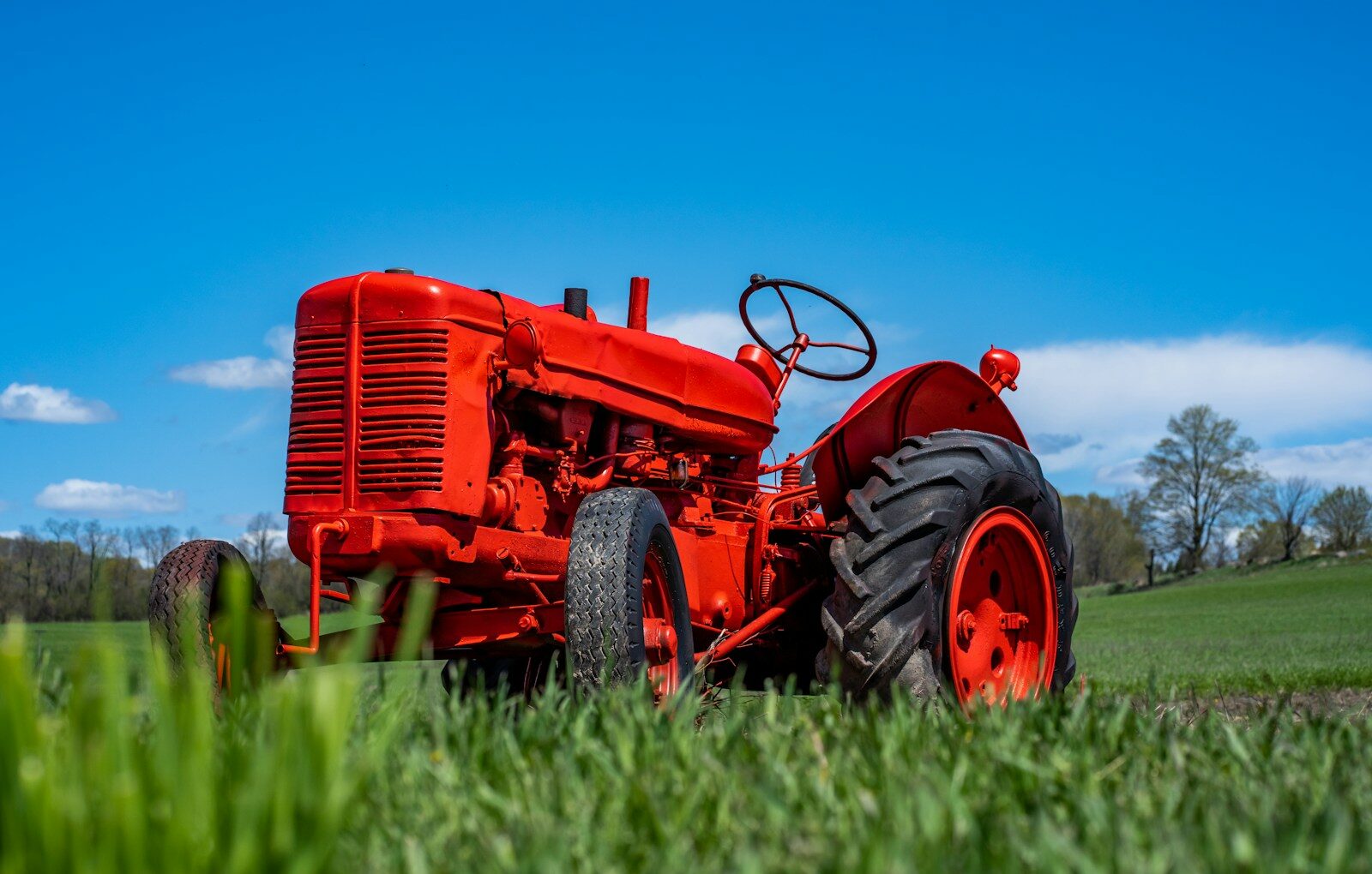 a red tractor is parked in the grass