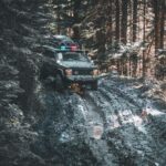 a truck driving through a forest filled with snow