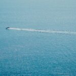 A boat leaves a white wake on the blue ocean.