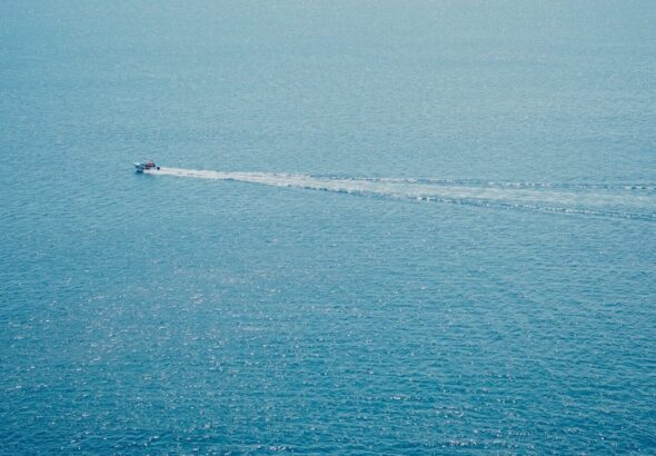 A boat leaves a white wake on the blue ocean.