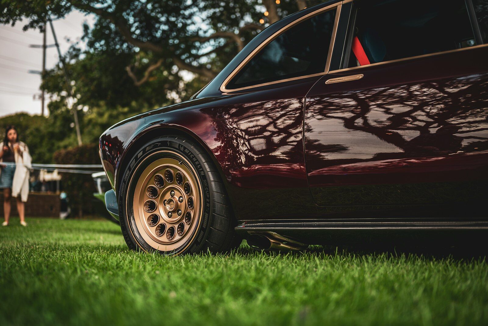 Close-up of a vintage burgundy car on grass.