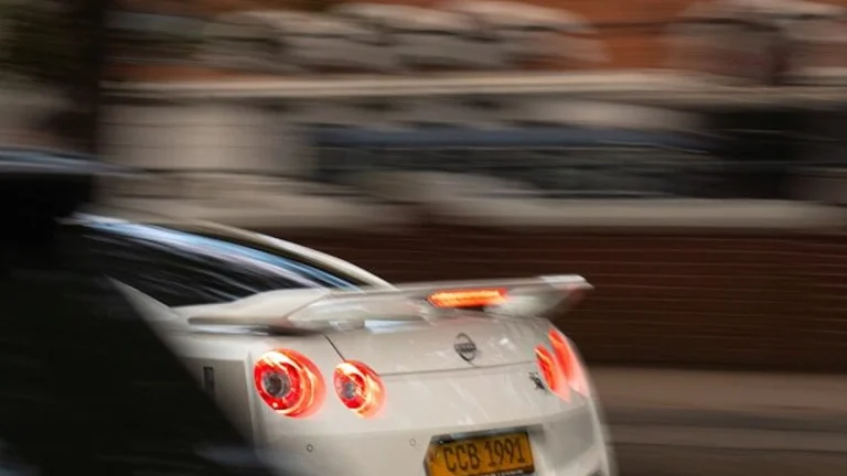 White sports car with glowing taillights in motion.