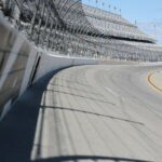 A racetrack curve and grandstands are shown.
