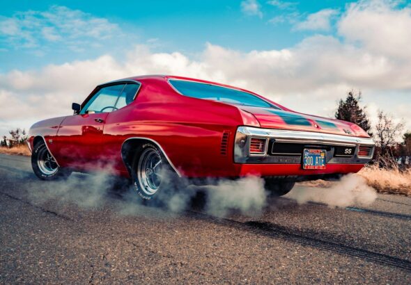 red chevrolet camaro on gray asphalt road under blue and white sunny cloudy sky during daytime