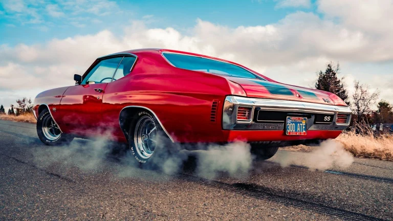 red chevrolet camaro on gray asphalt road under blue and white sunny cloudy sky during daytime