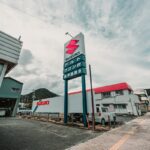 Suzuki dealership with a large sign and buildings.