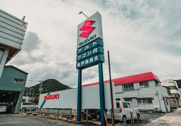 Suzuki dealership with a large sign and buildings.