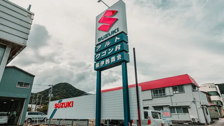 Suzuki dealership with a large sign and buildings.