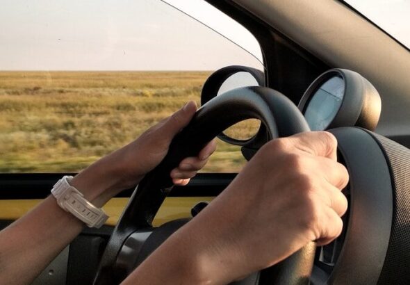person with white watch driving car
