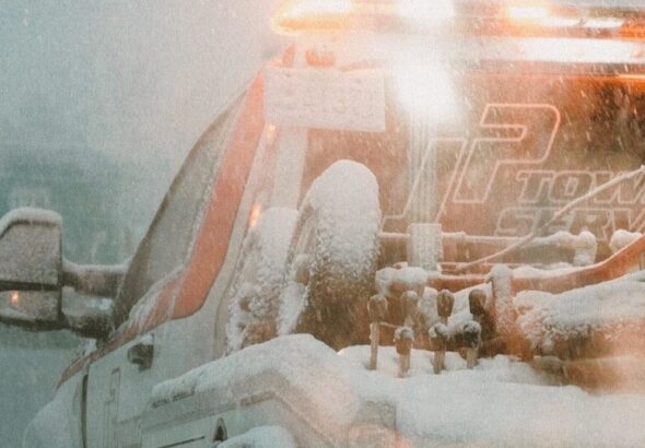 a white truck driving down a snow covered road