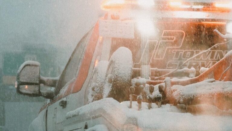 a white truck driving down a snow covered road