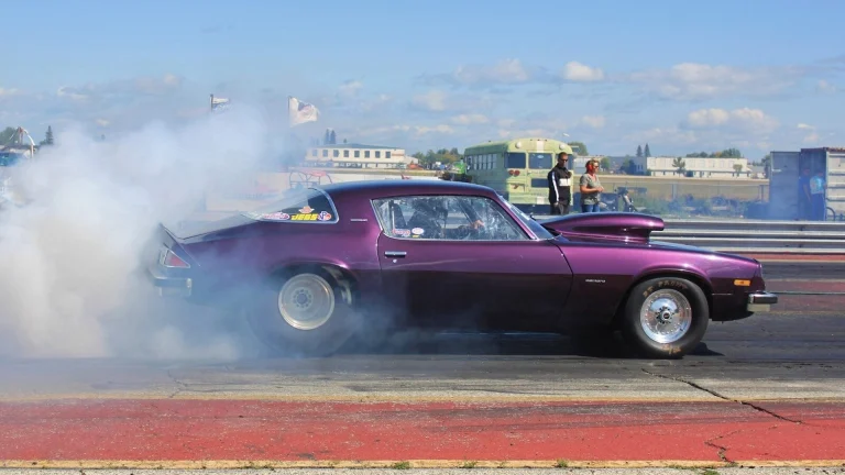 purple coupe burning out on road during daytime